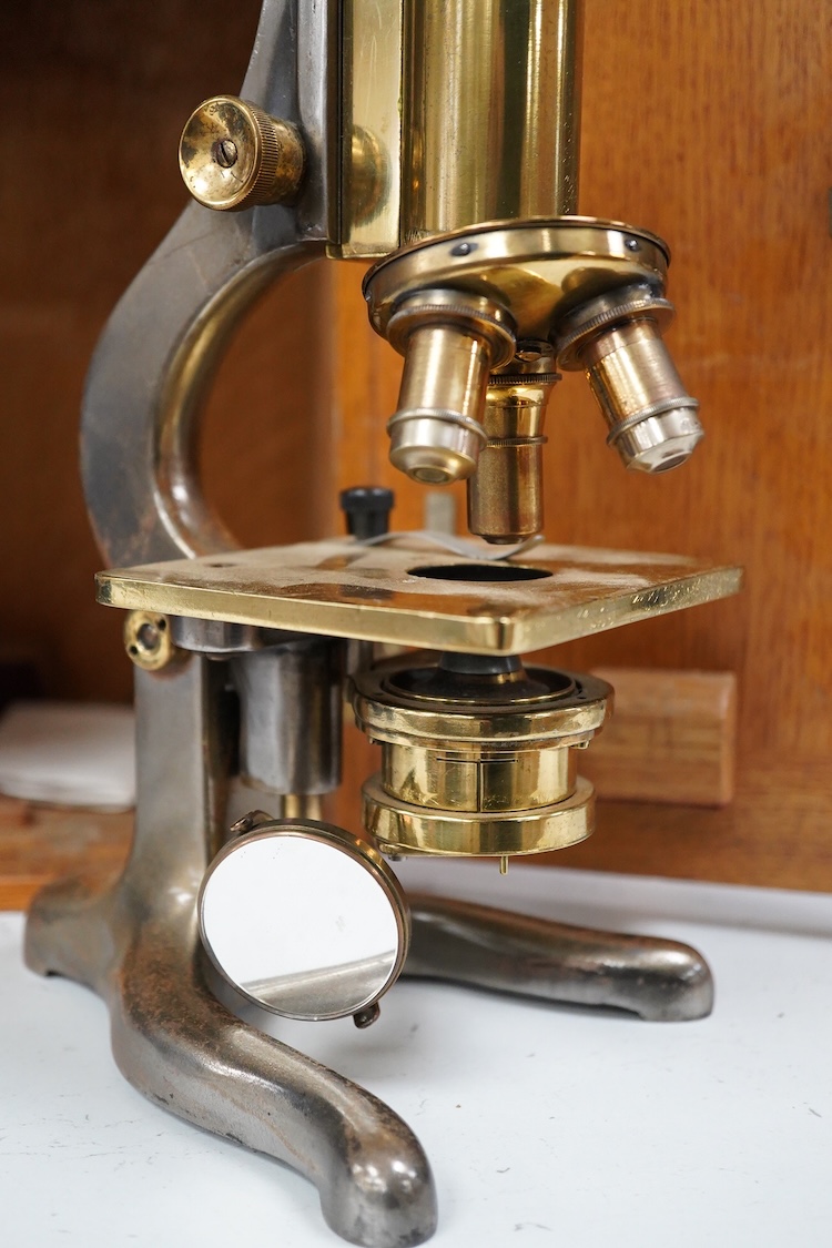 An early 20th century oak cased brass ‘Kima’ microscope by W. Watson & Sons Ltd. London, with engraved serial number under the maker’s name; 53622, with two alternative lenses in fitted compartments, microscope approxima